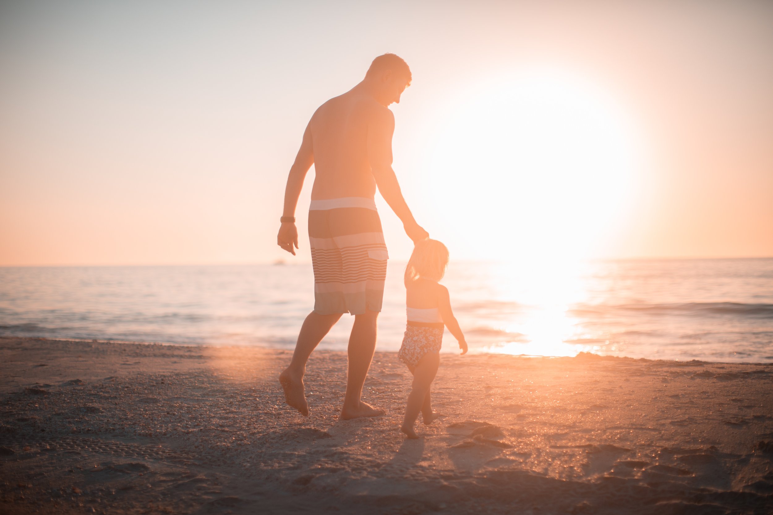 Hình ảnh cha và con gái đi bộ trên bãi biển nắng ấm